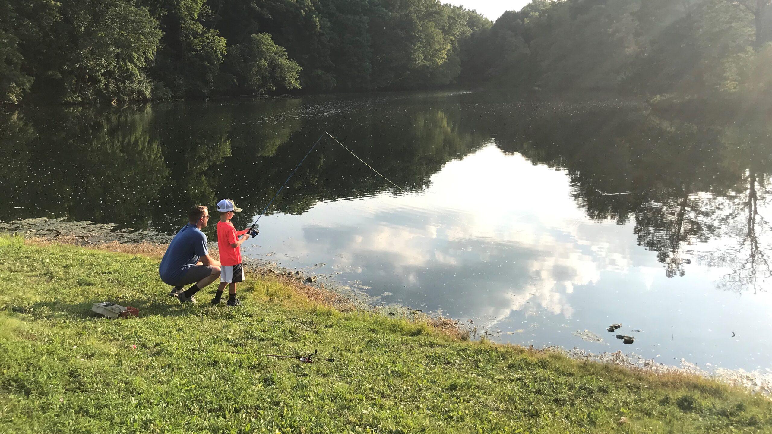 a boy and his dad fishing by the lake