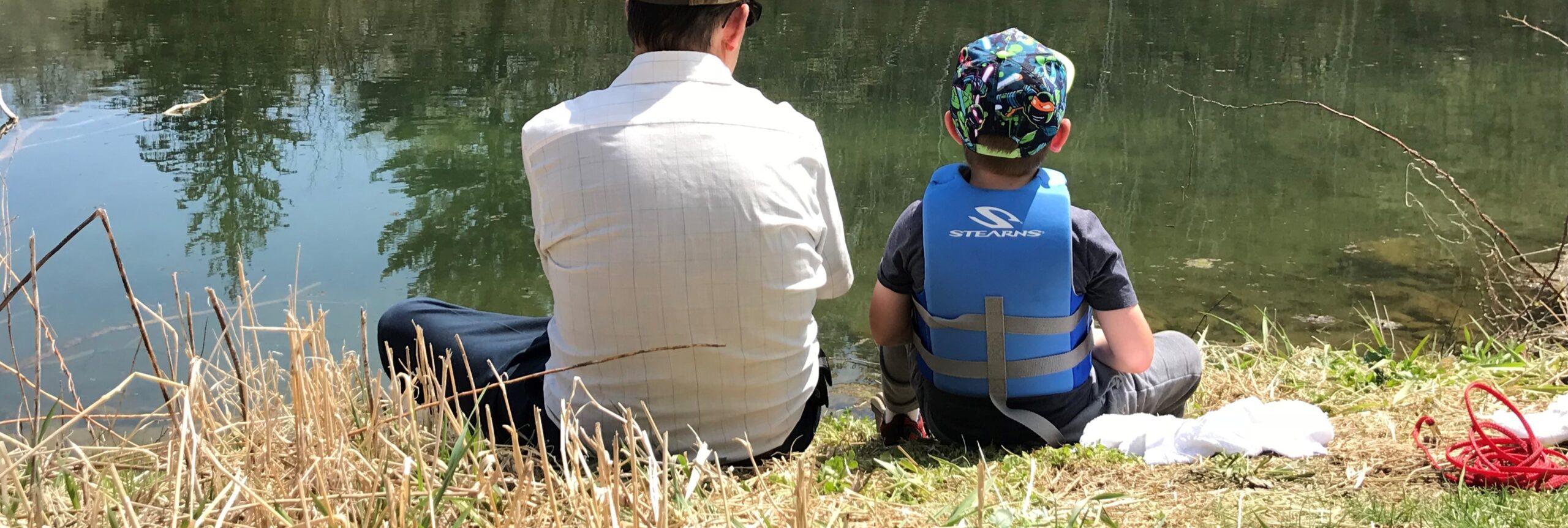 Boy fishing with his grandpa at a pond